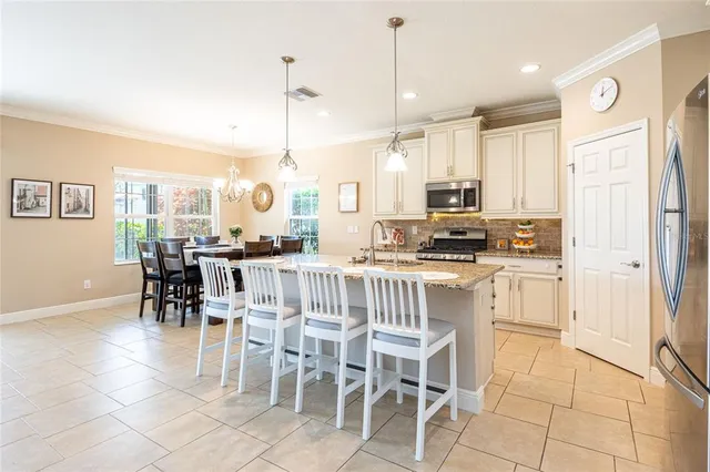 a kitchen with stainless steel appliances granite countertop a stove a refrigerator a oven a sink with a dining table and chairs