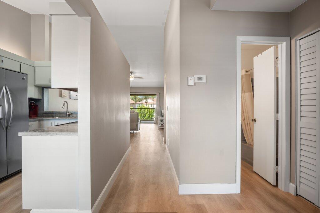 1402 Pinecrest Circle, Unit B Jupiter, FL 33458 - Photo 16 of 56 a view of a kitchen from the hallway with a window and a refrigerator