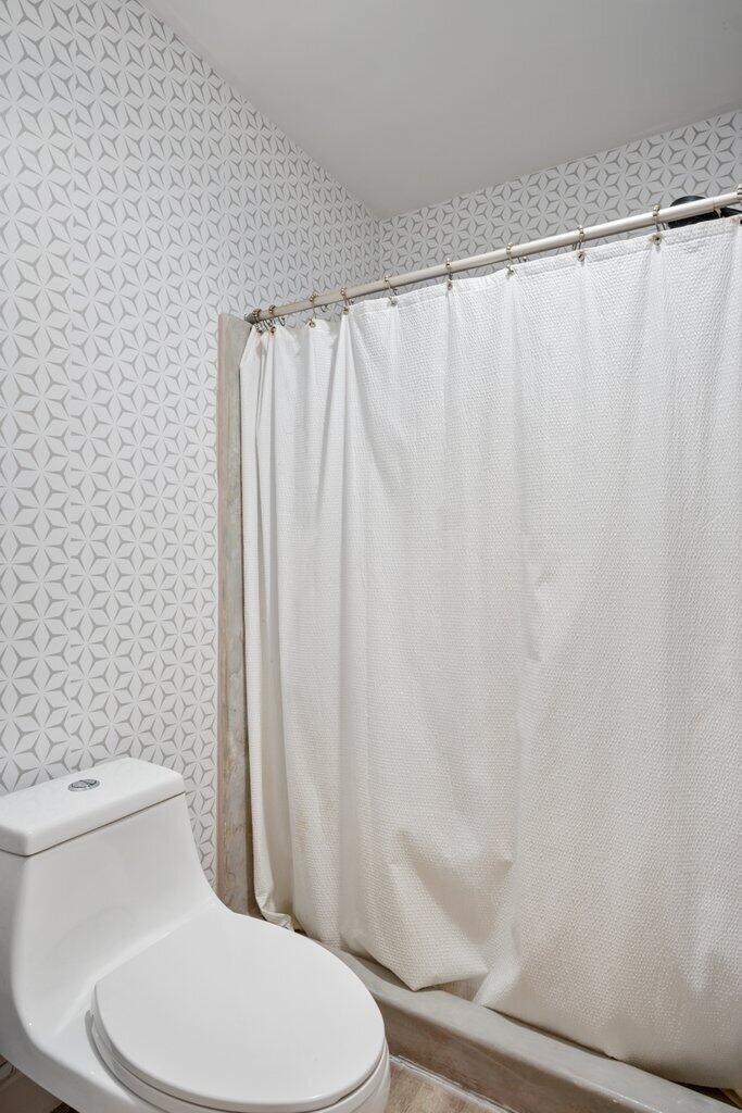 1402 Pinecrest Circle, Unit B Jupiter, FL 33458 - Photo 24 of 56 a white toilet sitting next to a shower curtain