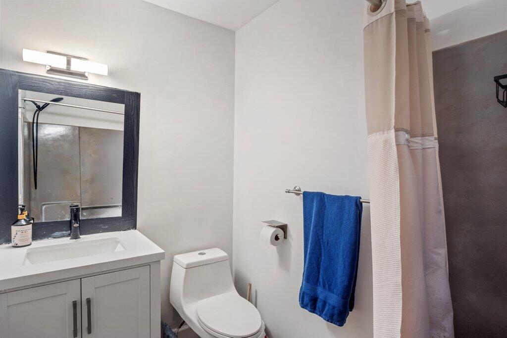 1402 Pinecrest Circle, Unit B Jupiter, FL 33458 - Photo 29 of 56 a bathroom with a toilet sink vanity and mirror