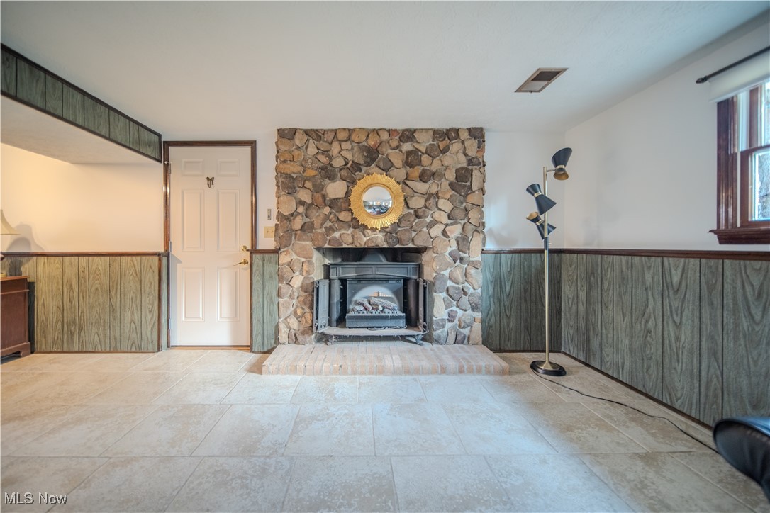 698 Albert Horning Road Atwater, OH 44201 - Photo 37 of 40 Unfurnished living room featuring wainscoting, wooden walls, and a stone fireplace