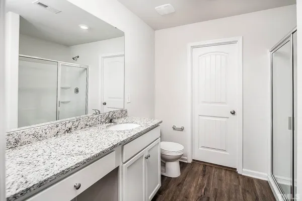 a bathroom with a granite countertop sink a toilet and a shower