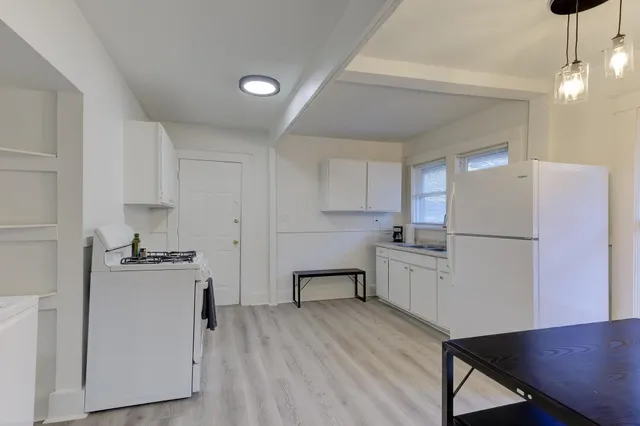 a hall with kitchen island granite countertop a sink and a stove with wooden floor