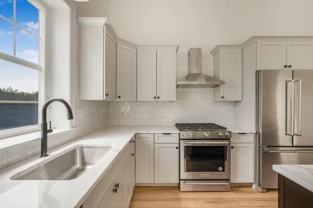 a kitchen with a stove windows and wooden floor