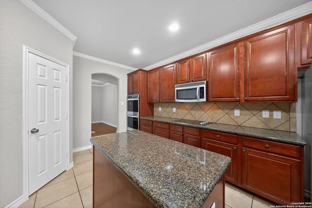 a kitchen with stainless steel appliances granite countertop wooden cabinets and granite counter tops