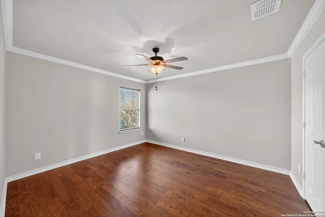an empty room with wooden floor and ceiling fan