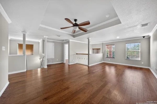 a view of an empty room with wooden floor and a window