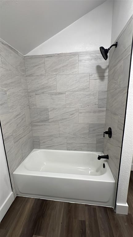 2102 East Overton Road, Unit B Dallas, TX 75216 - Photo 4 of 8 White bathtub with matte black fixtures, surrounded by light-toned tiled walls and wood-finish flooring
