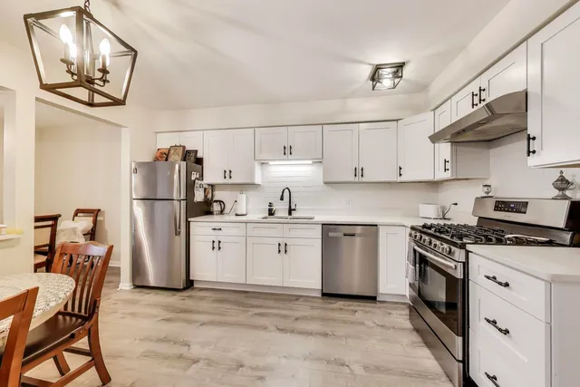a kitchen with stainless steel appliances granite countertop a stove refrigerator sink and cabinets