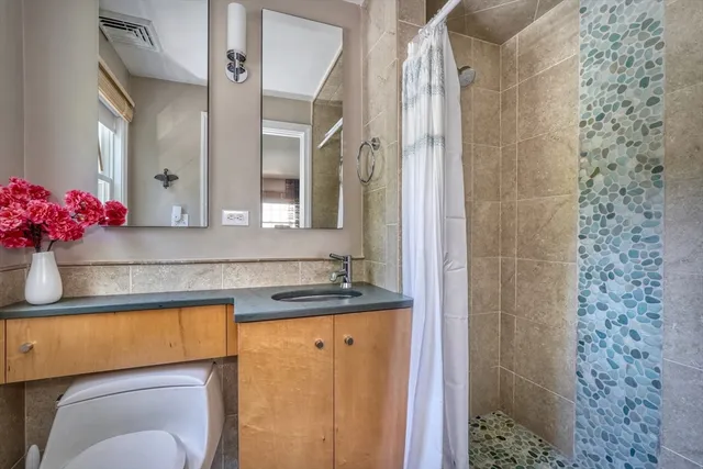 a bathroom with a granite countertop sink a toilet and shower