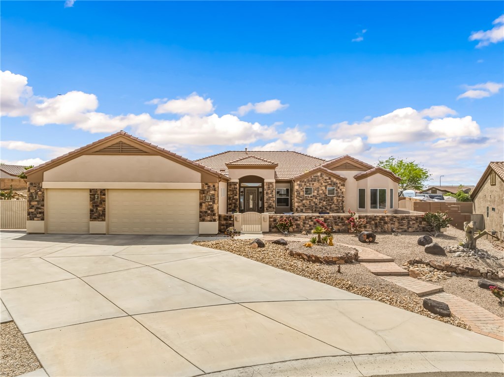 2708 Discovery Road Bullhead City, AZ 86442 - Photo 1 of 90 The property features a stone and stucco exterior, a tile roof, a two-car garage, and a concrete driveway