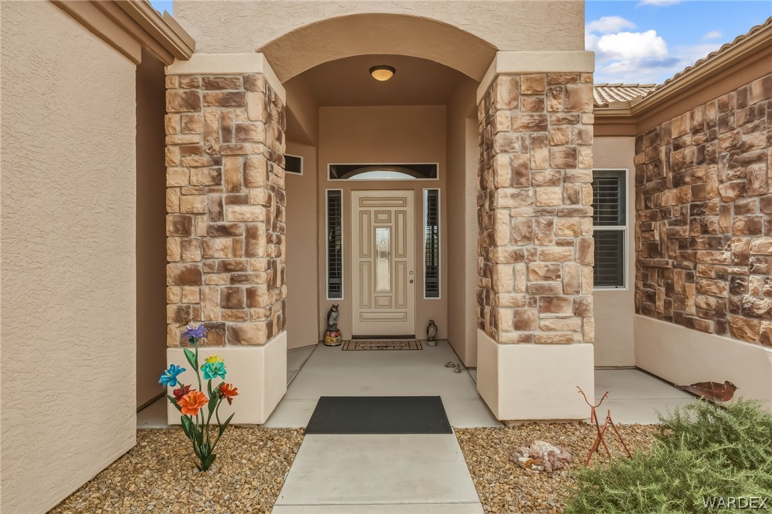 2708 Discovery Road Bullhead City, AZ 86442 - Photo 11 of 90 The property features an inviting entrance with stone veneer columns, an arched entryway, and a decorative front door with sidelight windows