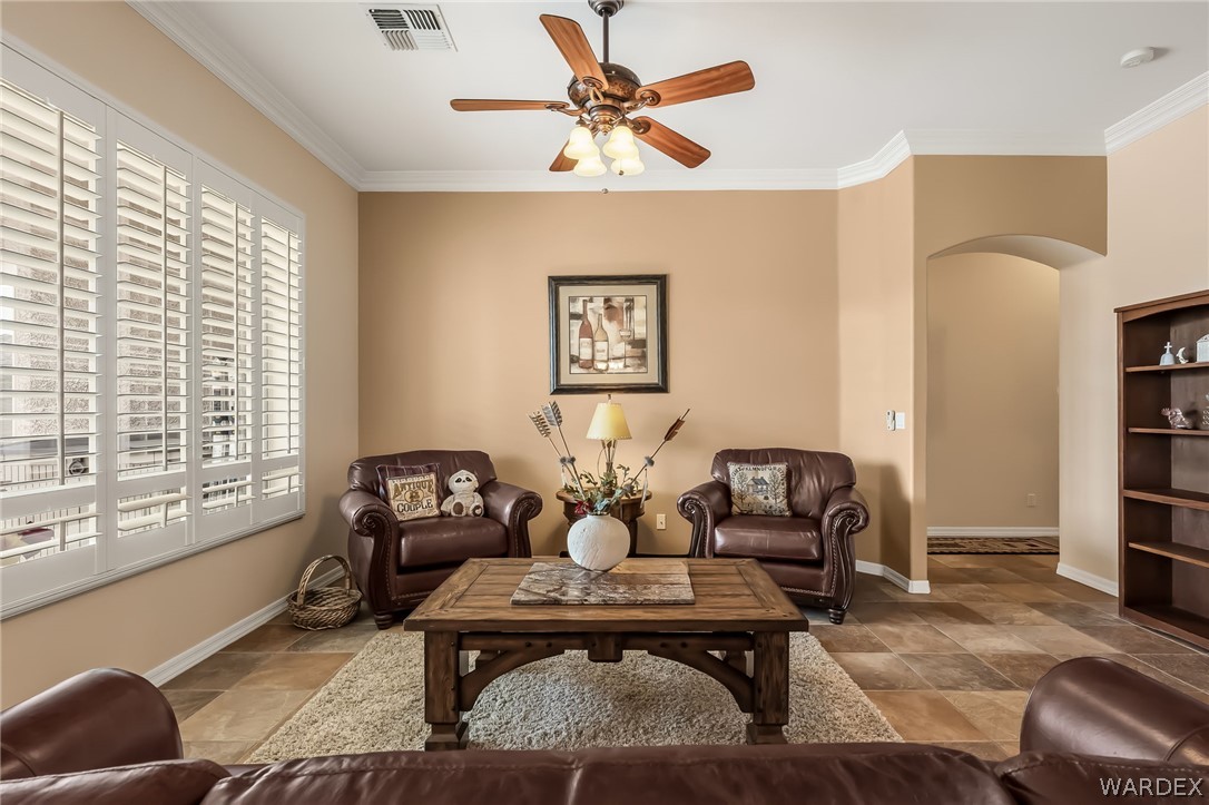 2708 Discovery Road Bullhead City, AZ 86442 - Photo 15 of 90 The living area features a ceiling fan, crown molding, and large windows with white louvered shutters