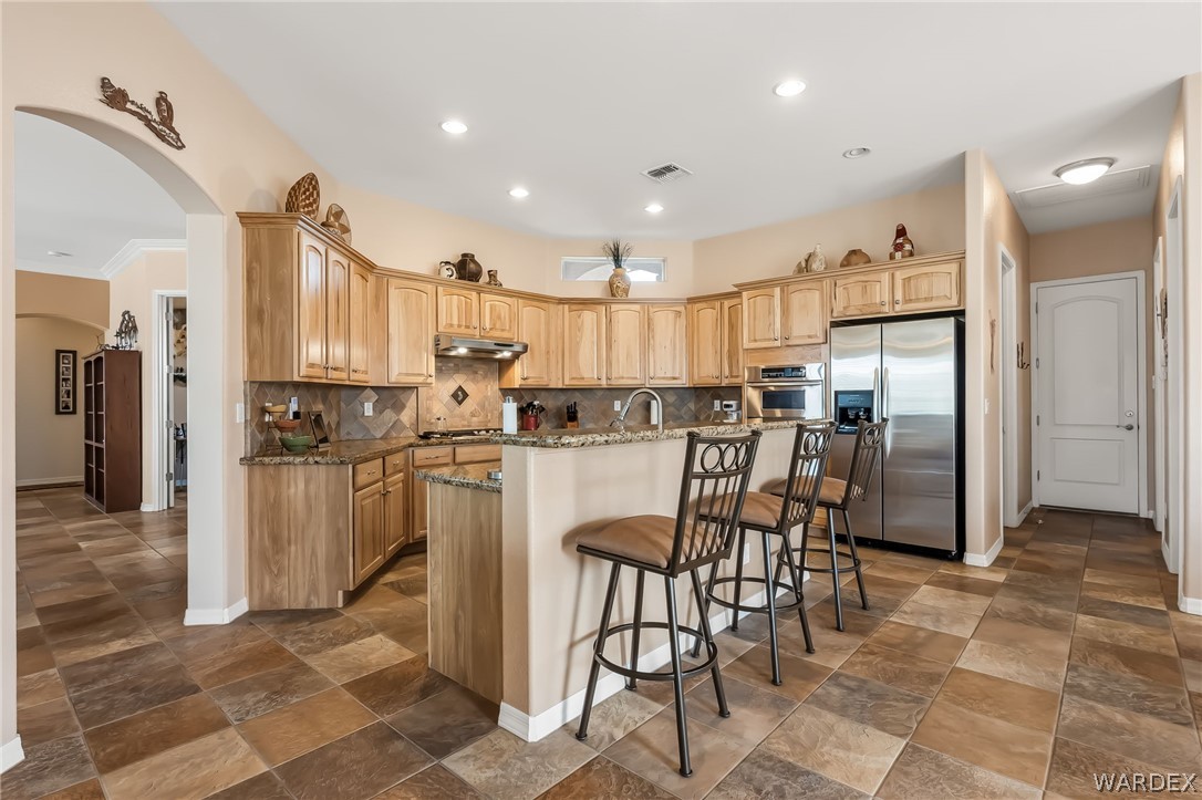 2708 Discovery Road Bullhead City, AZ 86442 - Photo 25 of 90 The property features a kitchen with wood cabinetry, granite countertops, and stainless steel appliances, including a double door refrigerator