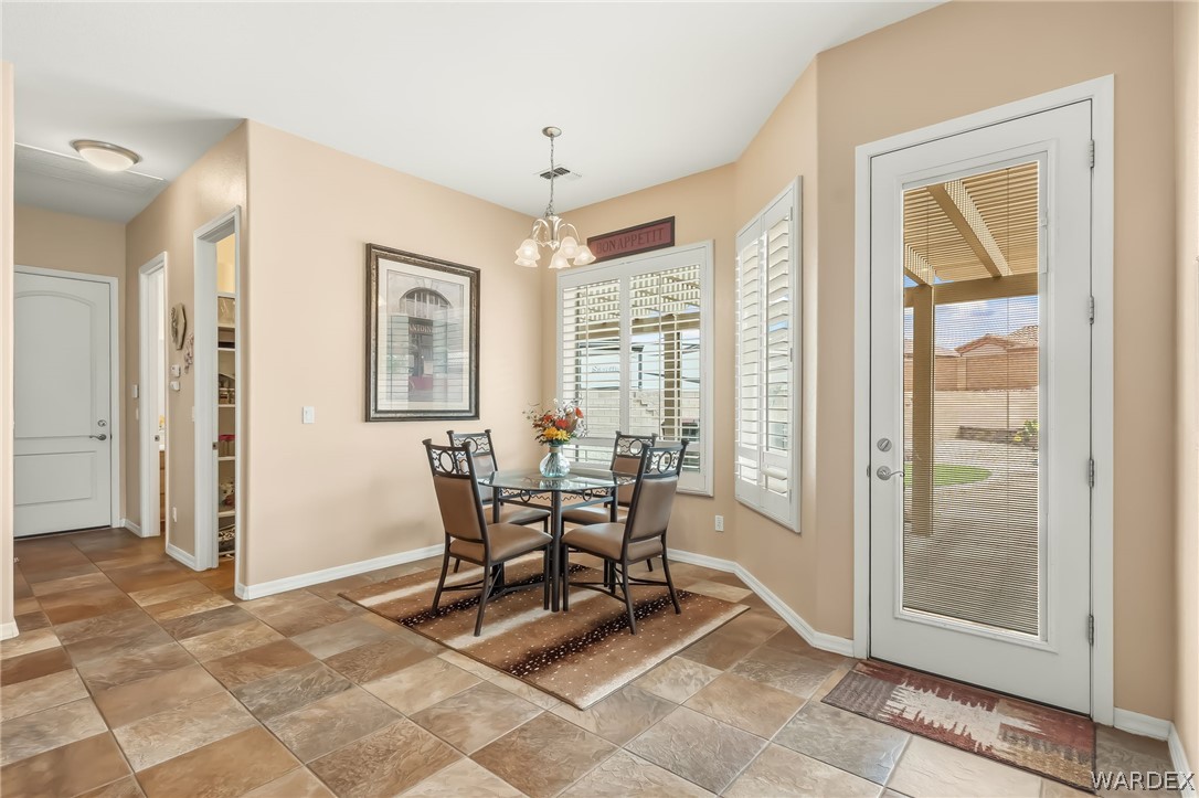 2708 Discovery Road Bullhead City, AZ 86442 - Photo 29 of 90 Dining area featuring tile flooring, a glass-top table with four chairs, and windows with white plantation shutters