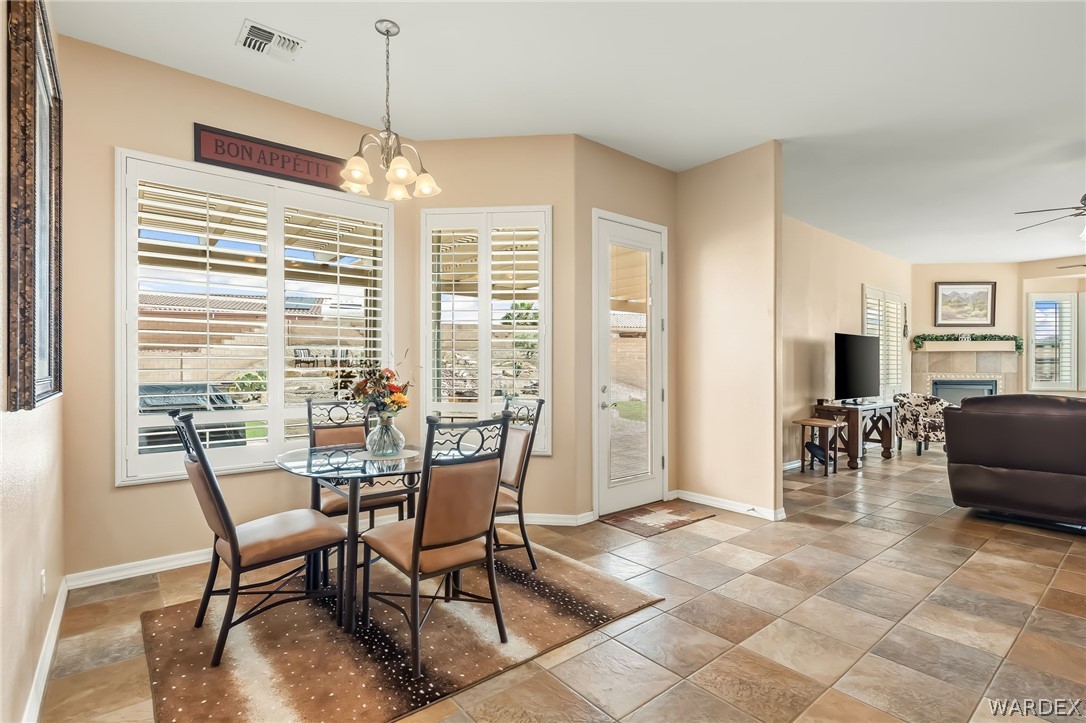 2708 Discovery Road Bullhead City, AZ 86442 - Photo 31 of 90 The property features a dining area with a glass-top table and four chairs, illuminated by an overhead chandelier