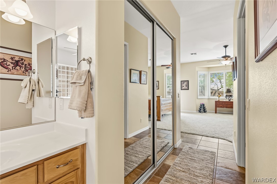 2708 Discovery Road Bullhead City, AZ 86442 - Photo 47 of 90 This property features a bathroom vanity with a white countertop and a mirror, located near a hallway with mirrored closet doors