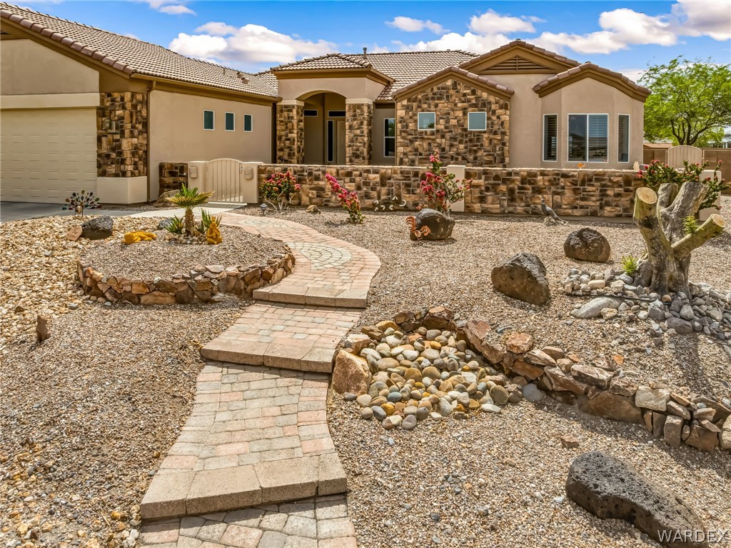 2708 Discovery Road Bullhead City, AZ 86442 - Photo 5 of 90 The property features a stucco and stone exterior, a tile roof, and a paved walkway leading to the entrance