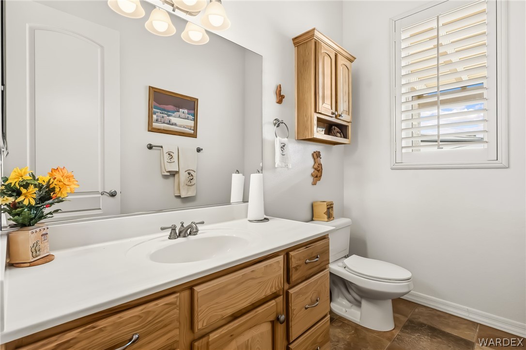 2708 Discovery Road Bullhead City, AZ 86442 - Photo 67 of 90 The bathroom features a vanity with a white countertop and natural wood cabinetry, a window with plantation shutters, and a toilet
