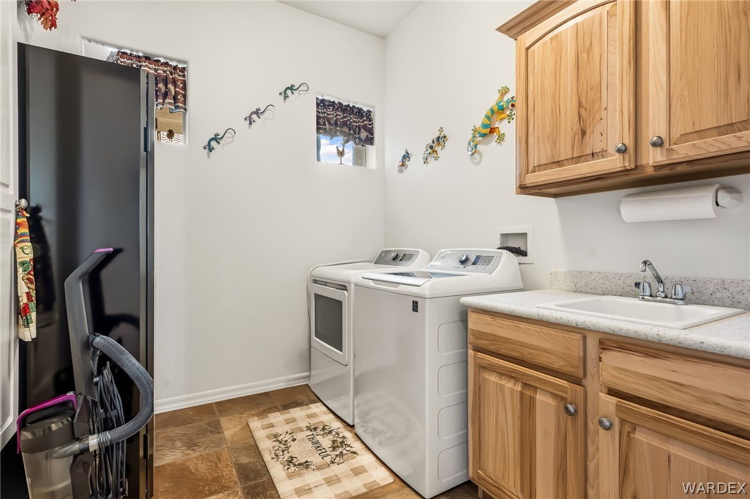 2708 Discovery Road Bullhead City, AZ 86442 - Photo 68 of 90 This utility space features light wood cabinetry with silver hardware, a white sink set into a light-colored countertop, and a durable tile floor