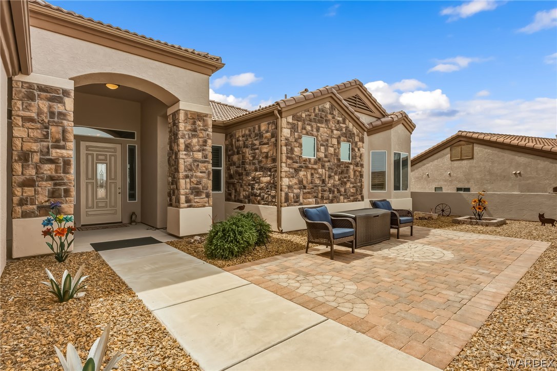 2708 Discovery Road Bullhead City, AZ 86442 - Photo 9 of 90 This property features an inviting entrance with stone accents, a paved walkway, and a private patio area with decorative pavers