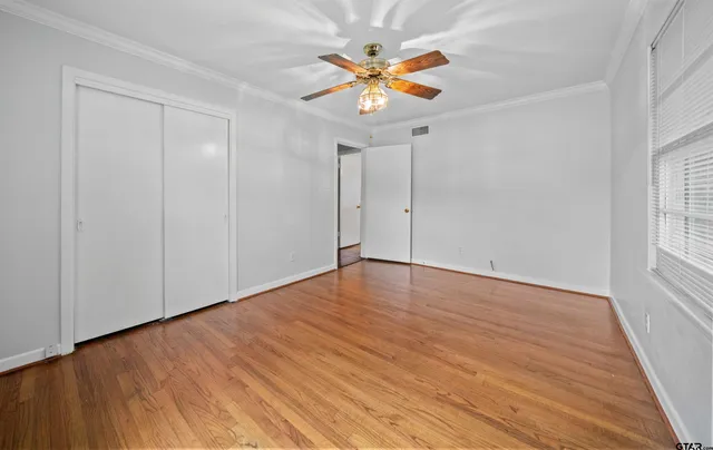 a view of an empty room with window and wooden floor