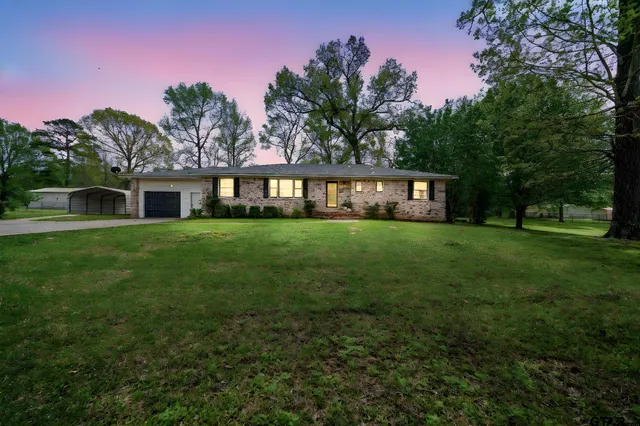 a view of a house with a big yard and large trees