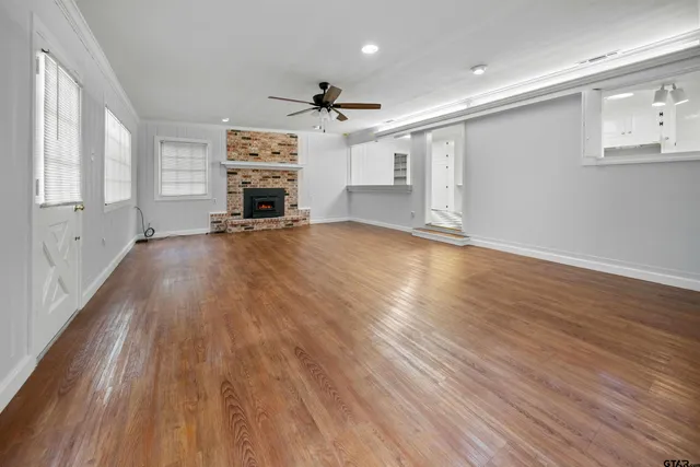 an empty room with wooden floor a ceiling fan and windows