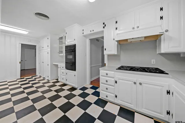 a kitchen with a checkered floor and white cabinets