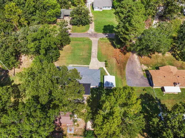 an aerial view of residential houses with outdoor space and trees