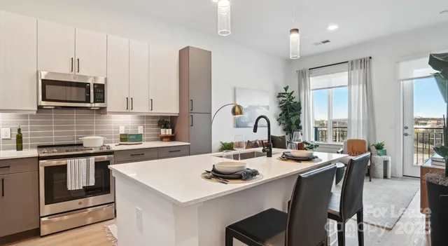 a kitchen with stainless steel appliances a sink a stove a table and chairs