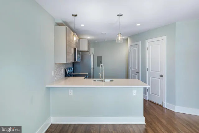 a room with kitchen island a sink and a stove top oven with wooden floor