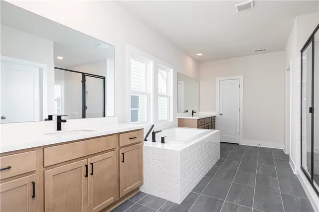 a large white bathroom with a double vanity sink a mirror and a bathtub