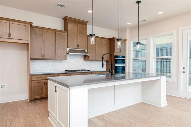 a kitchen with stainless steel appliances granite countertop a sink a stove and a refrigerator