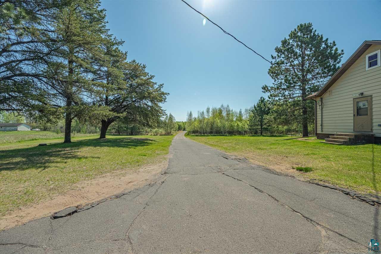 2581 O'Rourke Road Hibbing, MN 55746 - Photo 39 of 61 Paved driveway extending into a wooded landscape, bordered by a siding structure with a side entrance