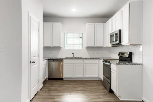 a kitchen with stainless steel appliances granite countertop a stove a sink and a microwave