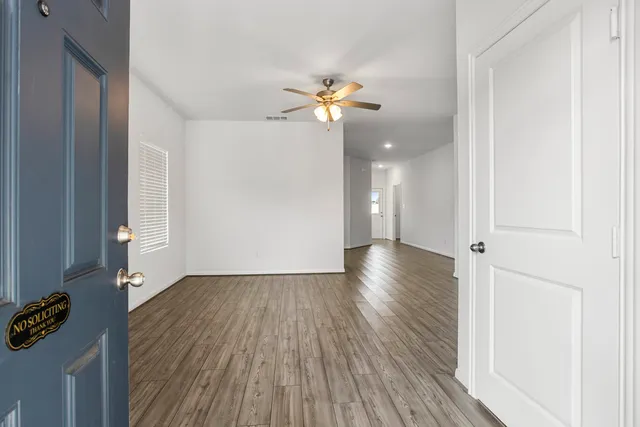 a view of a room with wooden floor and a ceiling fan