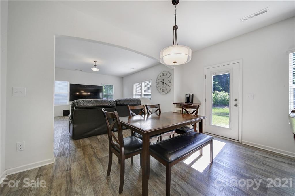 3097 Riker Street Clover, SC 29710 - Photo 18 of 39 a dining room with wooden floor a chandelier a wooden table and chairs