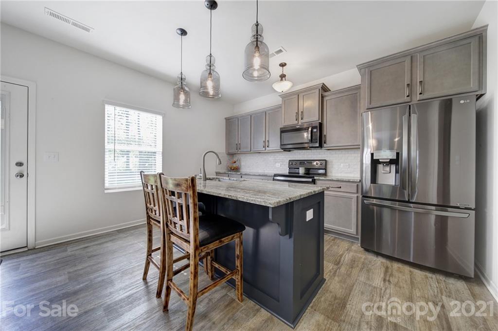 3097 Riker Street Clover, SC 29710 - Photo 19 of 39 a kitchen with stainless steel appliances granite countertop a refrigerator a sink dishwasher a dining table and chairs with wooden floor