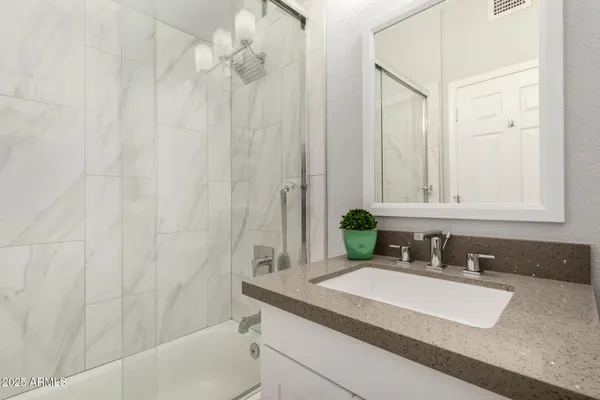 a bathroom with a granite countertop sink and a mirror a bathtub