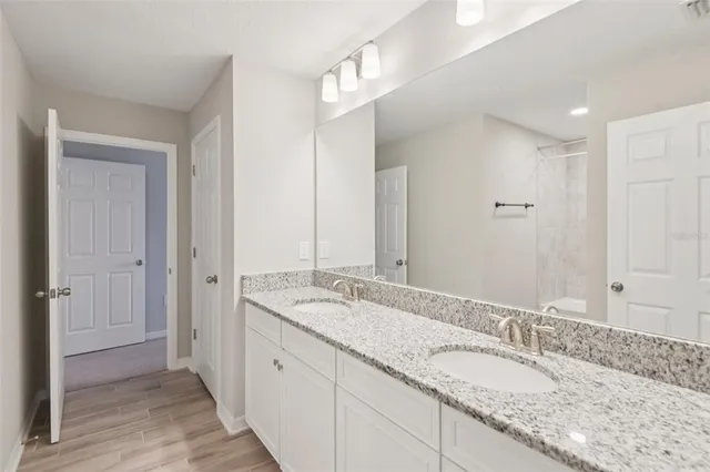a bathroom with a granite countertop double vanity sink and a mirror