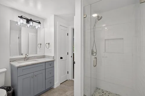 a bathroom with a granite countertop sink two mirror and shower