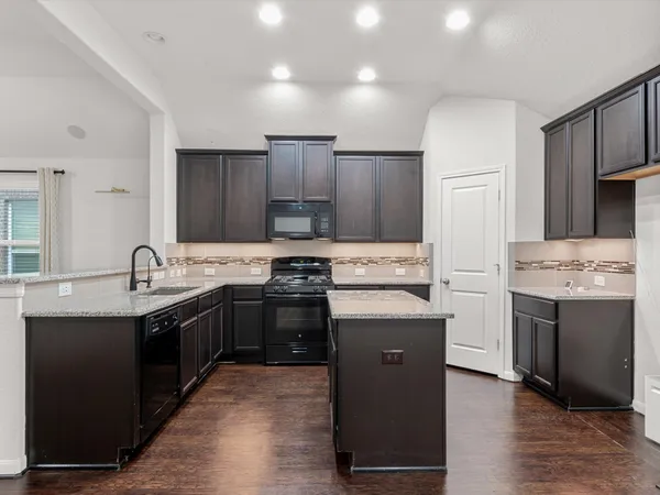 a kitchen with kitchen island granite countertop a sink stove and refrigerator