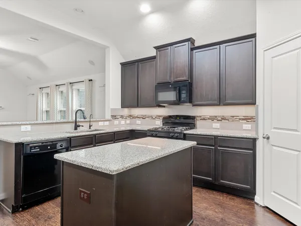 a kitchen with a sink and a stove top oven with wooden floor