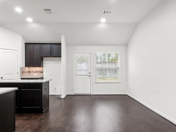 a view of an empty room with a kitchen and a window