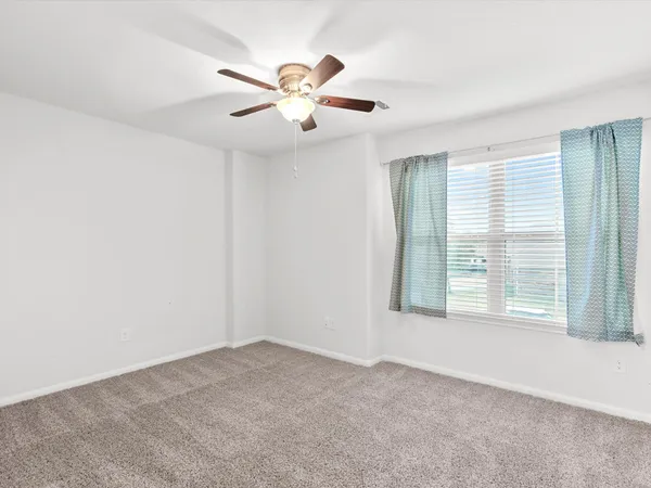a view of an empty room with chandelier fan and fire place