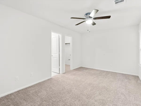 an empty room with a ceiling fan and a window