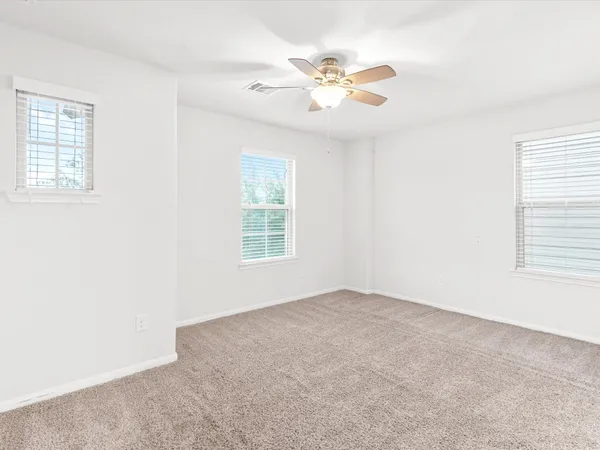 an empty room with windows and fan
