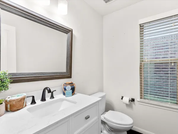a bathroom with a granite countertop sink mirror vanity and toilet