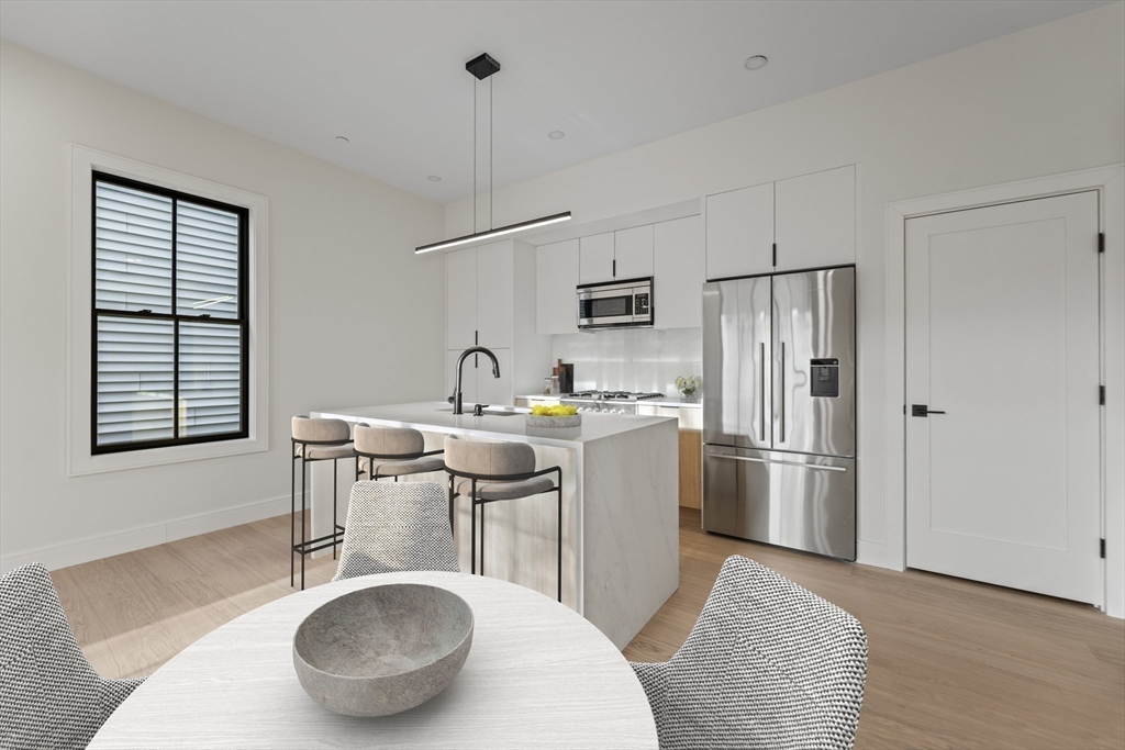 224 West 9th Street, Unit 4 Boston, MA 02127 - Photo 3 of 22 a kitchen with stainless steel appliances a dining table chairs and a refrigerator